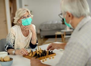  Caregiver And Senior talking in a living facility wearing ppe